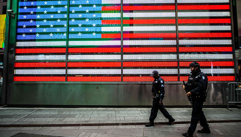 Two police officers walking in front of LED American flag