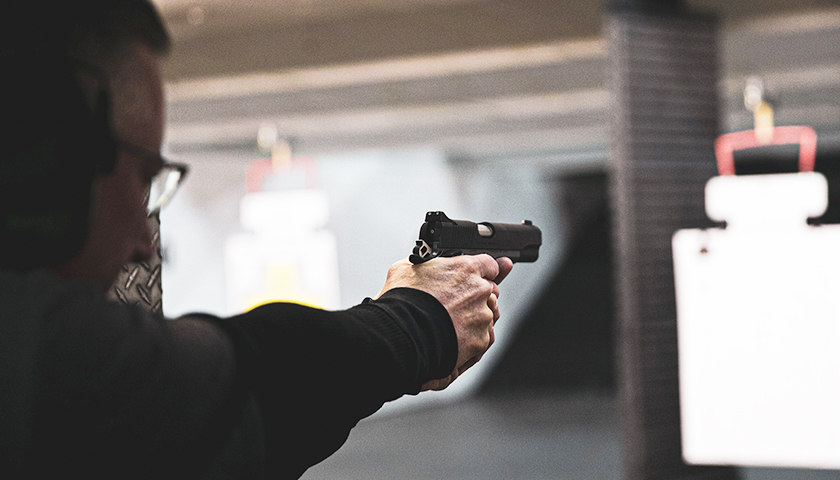 Person shooting a hand gun in a shooting range