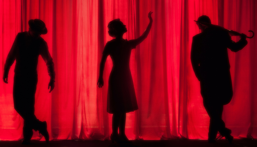 Silhouette of three performers onstage